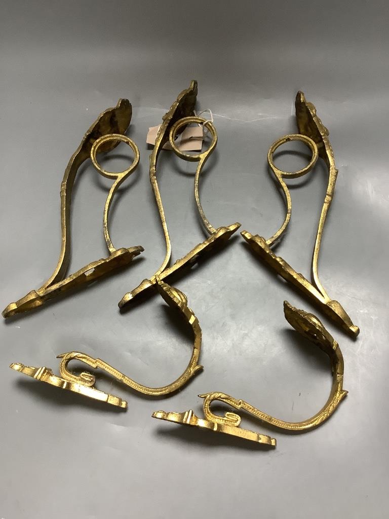 A pair of French ornate gilt curtain tiebacks and a set of three similar curtain brackets